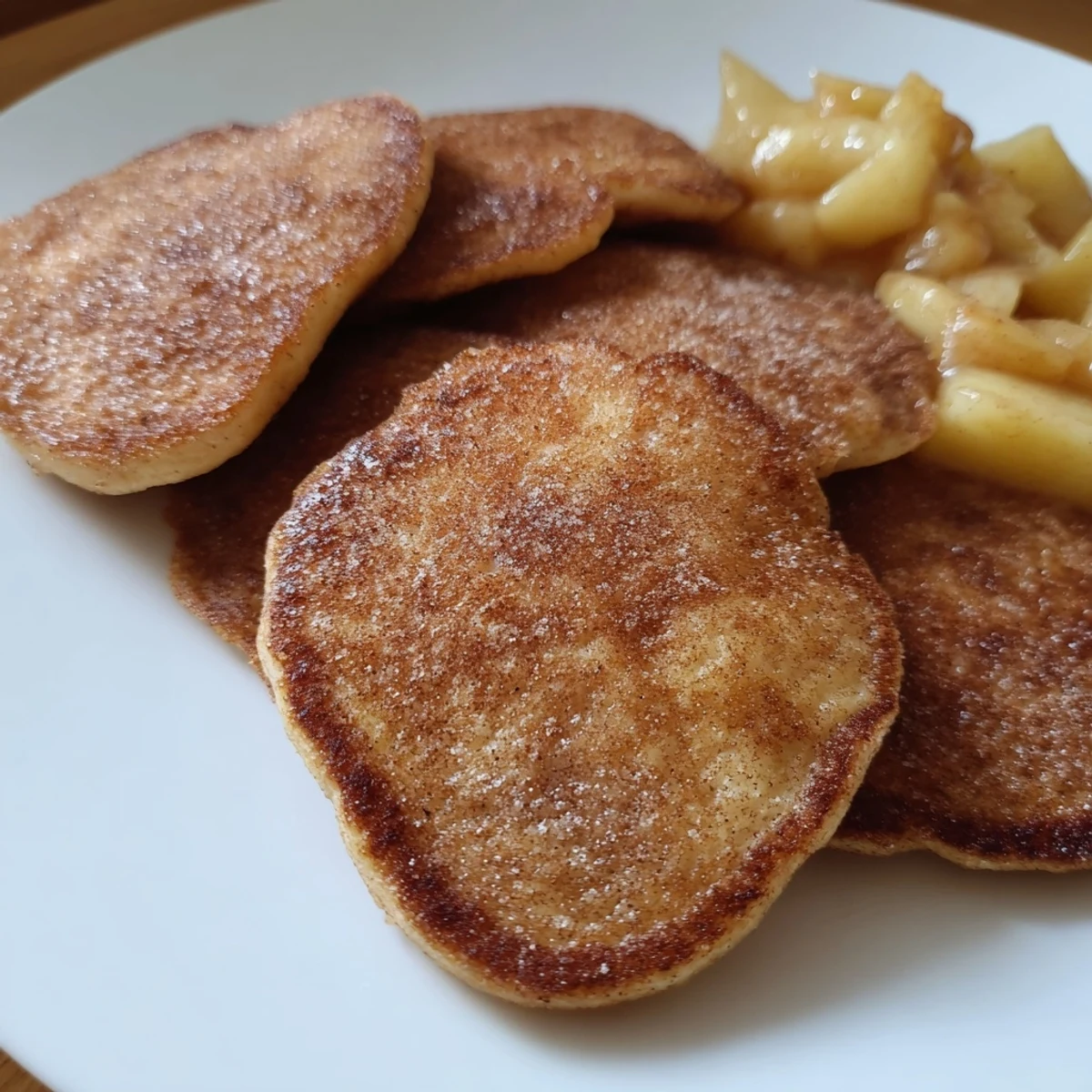 Fluffy golden Quarkkeulchen served with sweet apple compote: a comforting German breakfast treat.