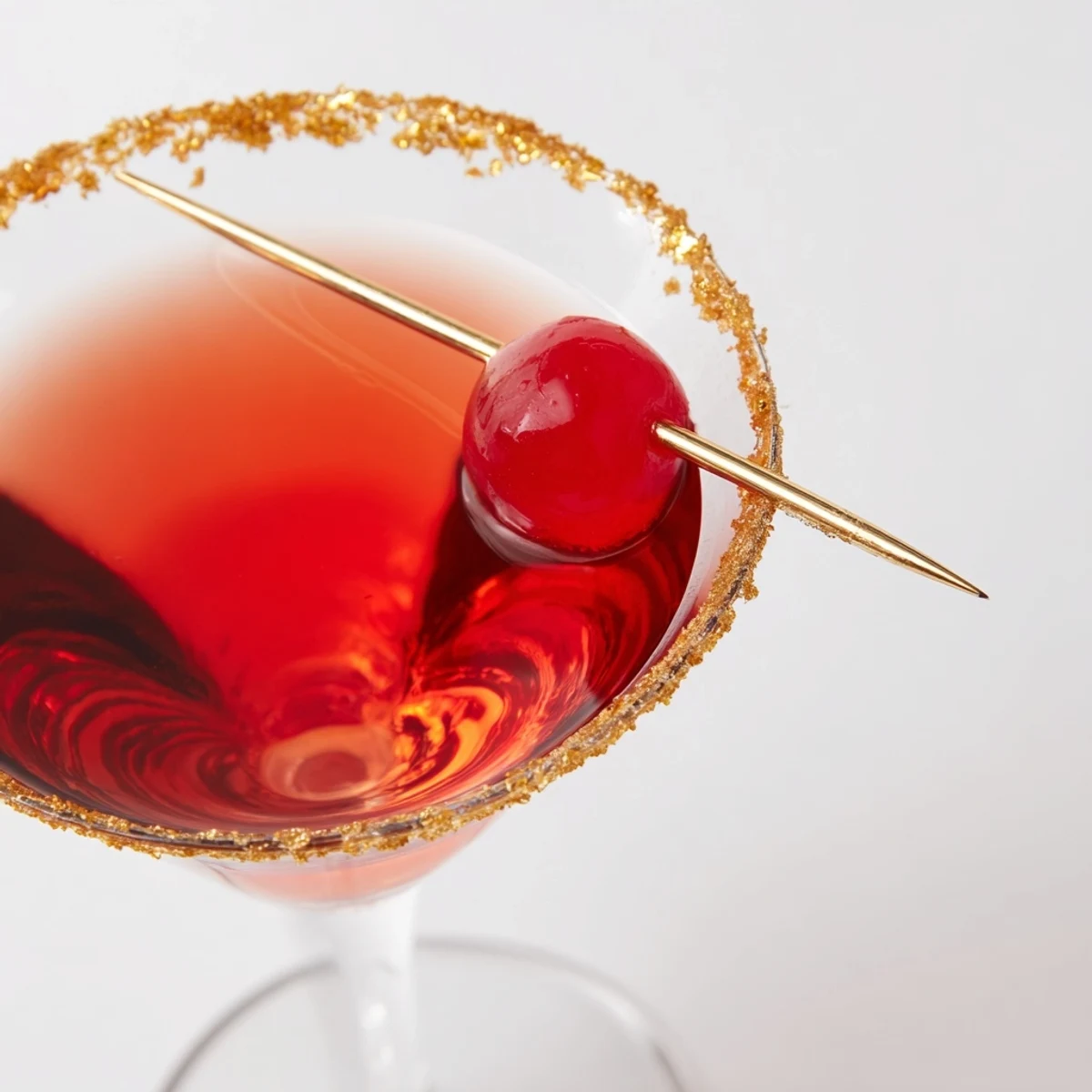 Close-up of a glamorous Rococo Kirsch Martini cocktail, its golden rim catching the light perfectly.