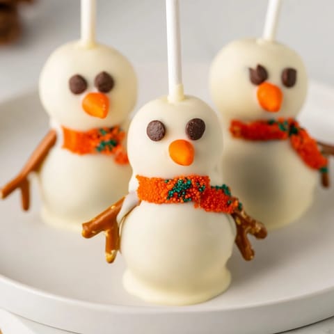 These festive Oreo Snowman Cake Pops feature a smooth white chocolate coating and pretzel arms.