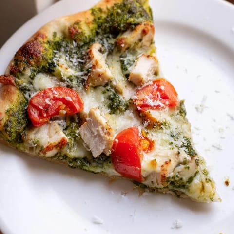 Saftiges Hühnchen und cremiger Mozzarella auf duftendem Basilikum-Pesto, belegt auf einer dünnen Pizza.
