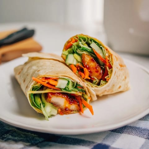 Gesunder chicken wrap mit Honey Chili Crunch und frischem Gemüse im weichen Tortilla, ideal für schnelle Mittagessen.