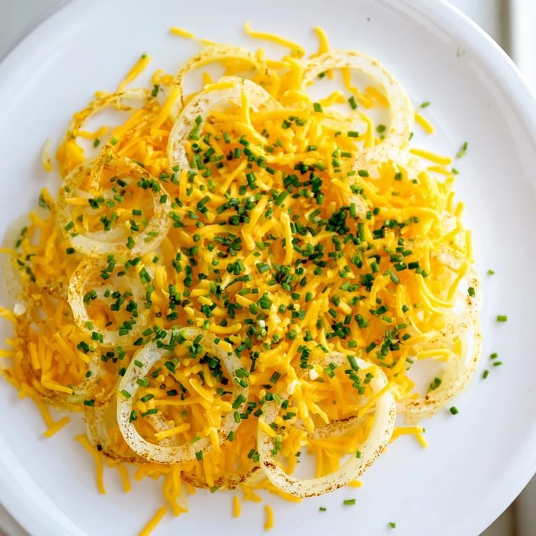 Ein Nahaufnahmenblick auf selbstgemachte, goldene Zwiebel-Käse-Chips, garniert mit frischen Kräutern.